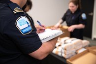 Tabac - 16 - <p>Inspecteurs consignant dans un document les articles saisis, dont des cigarettes de contrebande</p>