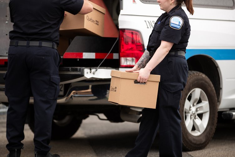 Tabac - 17 - <p>Inspecteurs chargeant des caisses de cigarettes de contrebande dans une camionnette de Revenu Québec</p>