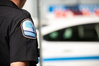 Tabac - 02 - <p>Badge sur l'uniforme d'un inspecteur de Revenu Québec et autopatrouille de Revenu Québec en arrière-plan</p>