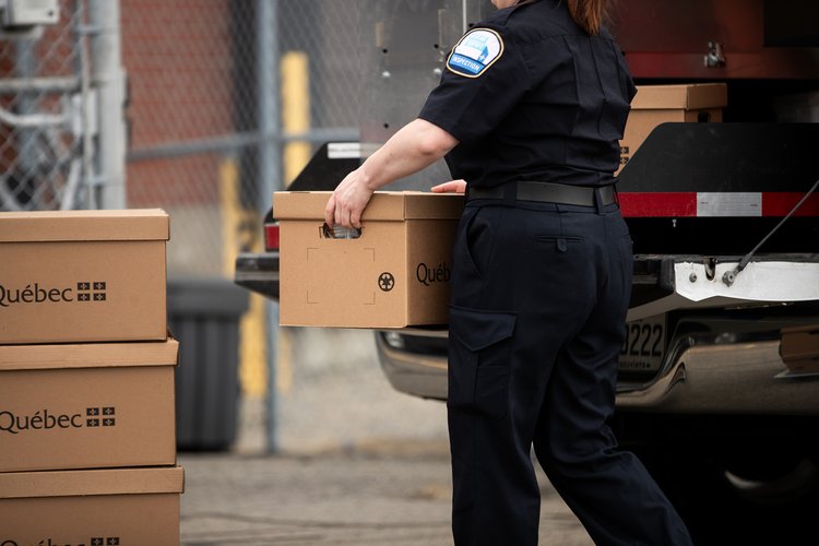 Tabac - 18 - <p>Inspectrice déchargeant des caisses de cigarettes de contrebande d'une camionnette de Revenu Québec</p>